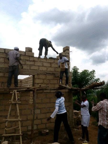 Community members working together to build a village structure